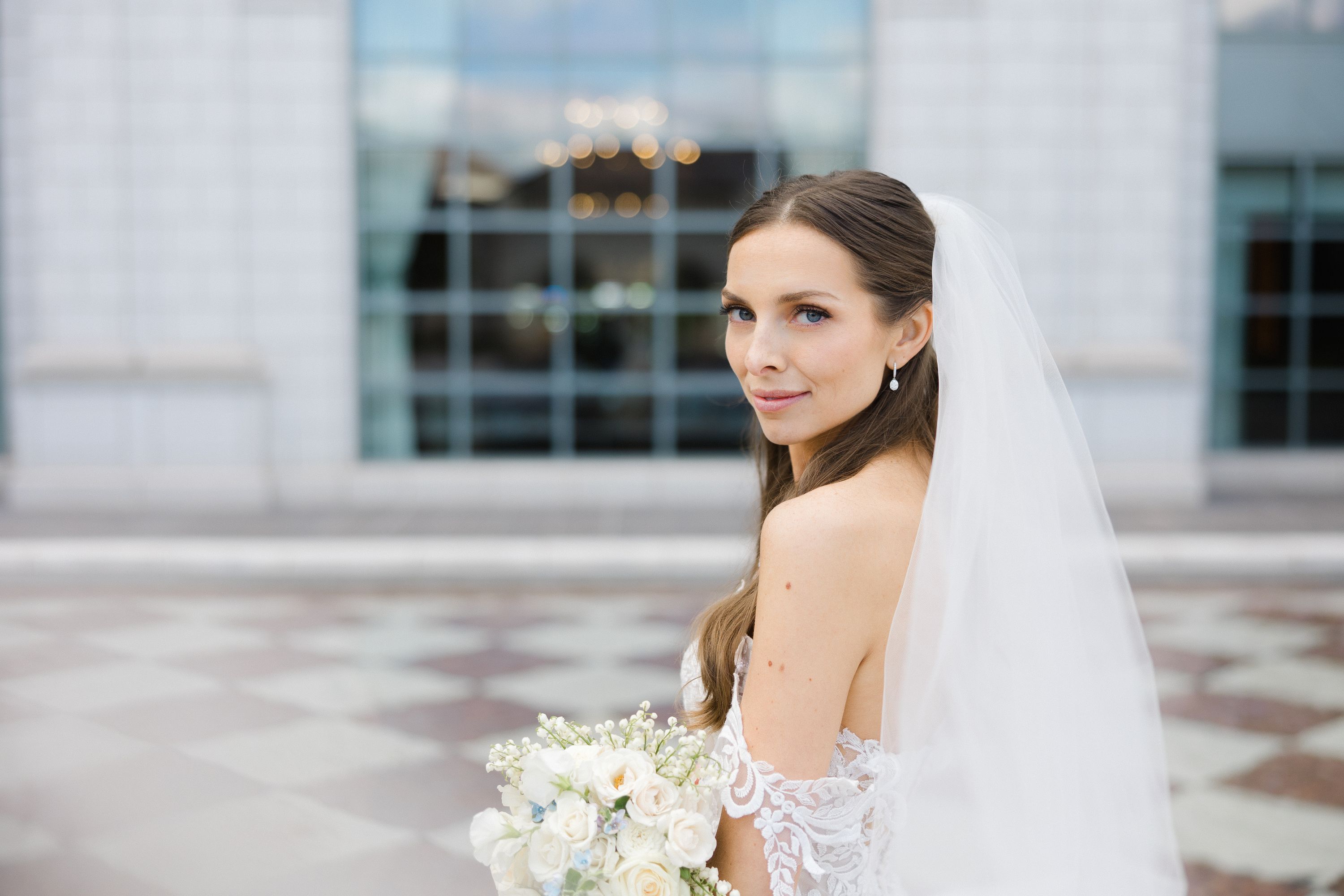 Bride poses for a photo in the Grand America courtyard with stunning marble backdrop.