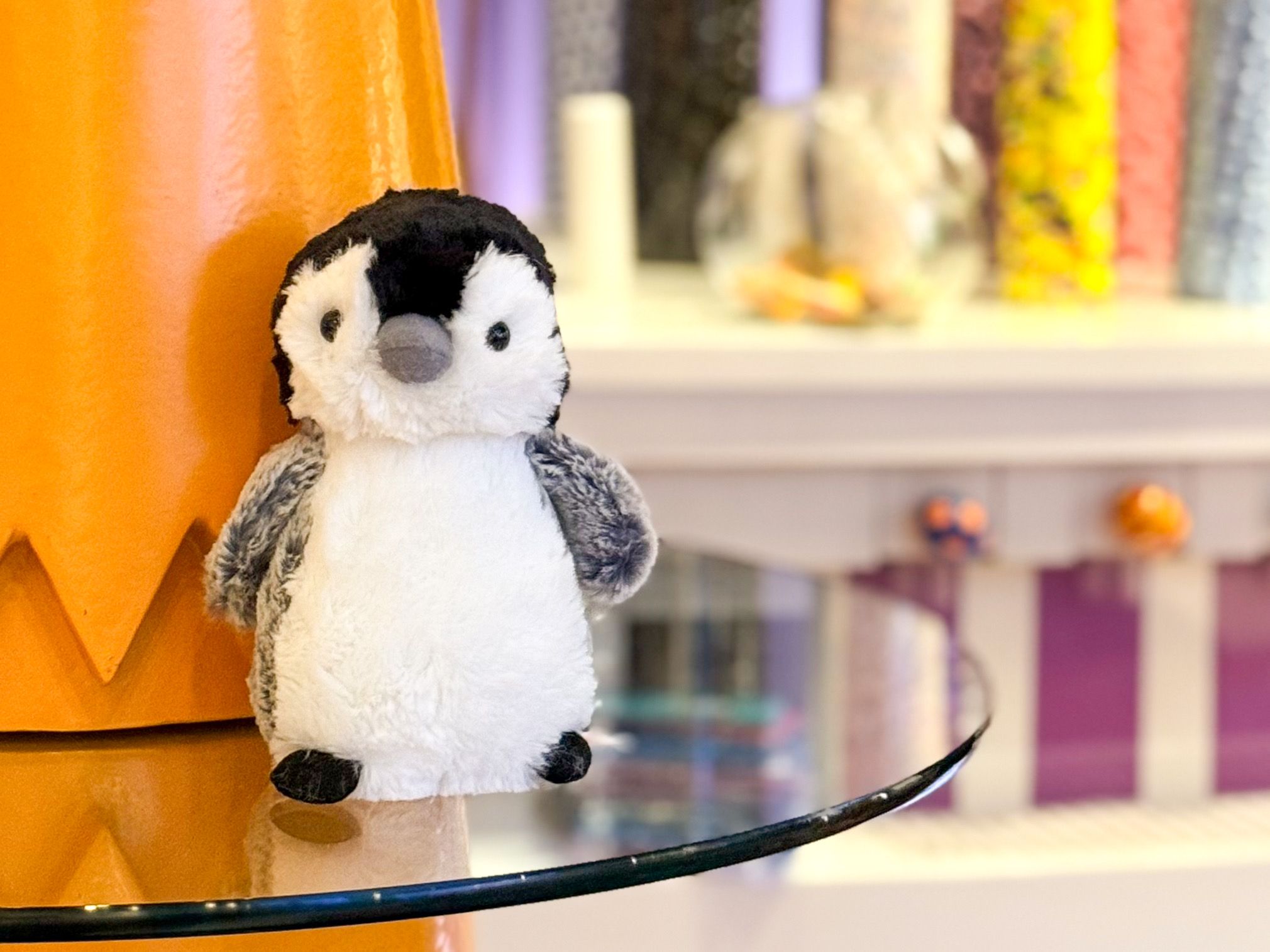 Plush penguin toy on a table in front of a wall of candy