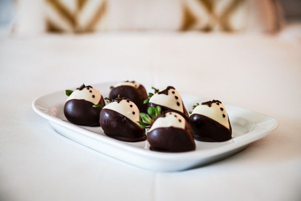 Plate of chocolate covered strawberries on a bed