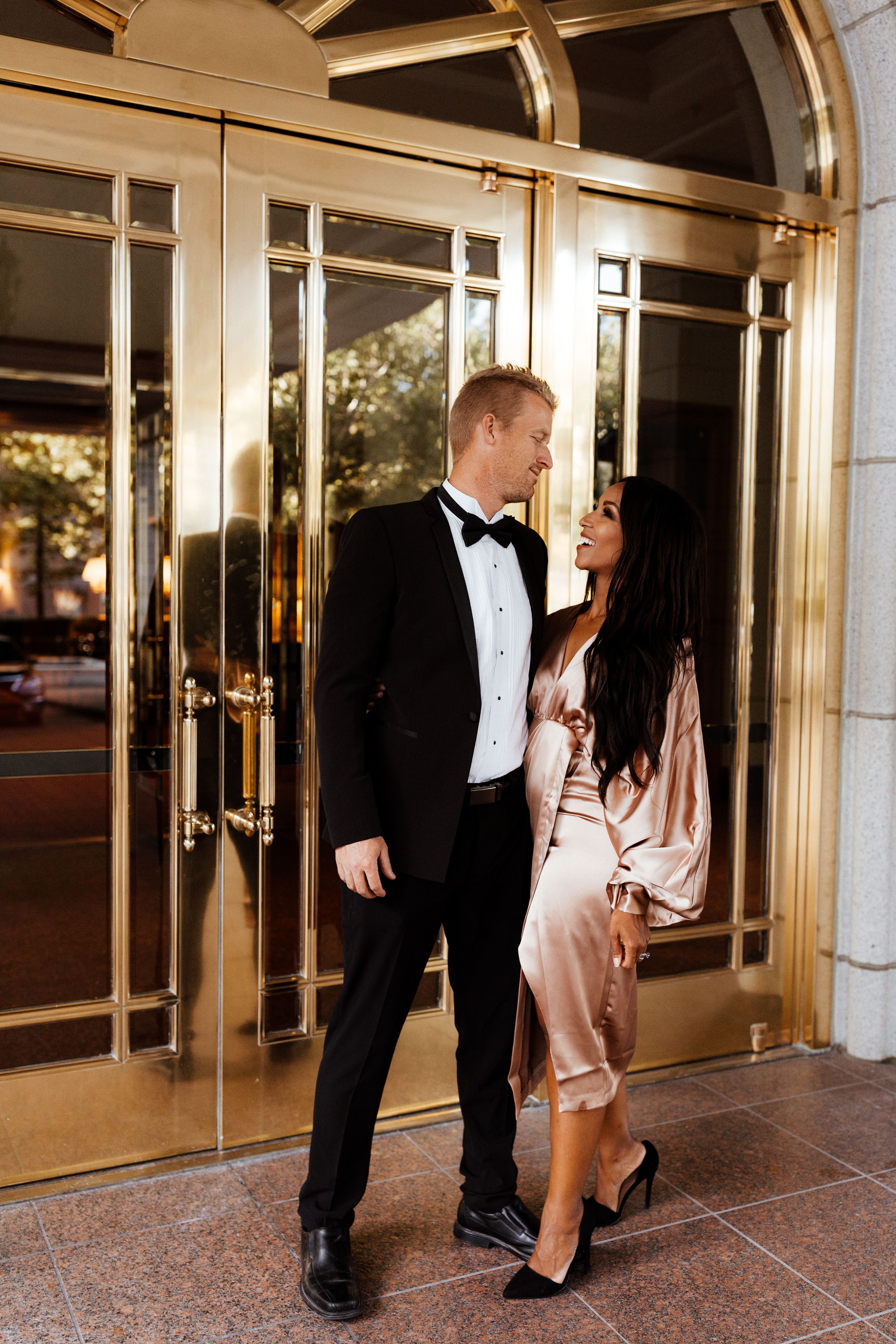 Couple standing outside of gold doors dressed in formal clothes